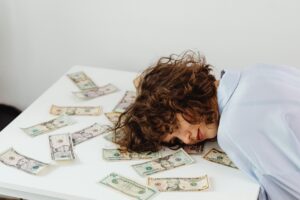 Person resting on money-covered table.
